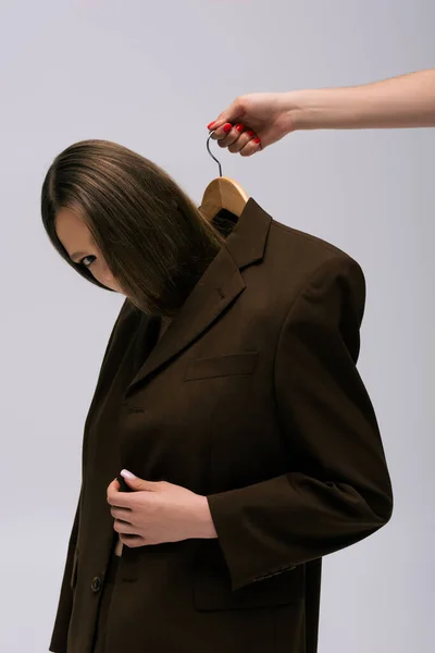 Woman holding hanger with model in brown blazer isolated on grey — Photo de stock