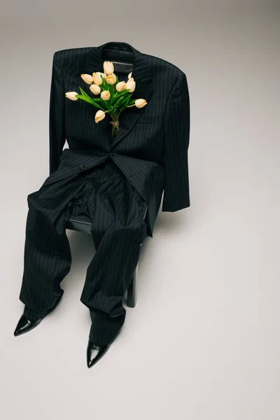 High angel view of blooming tulips and blue stylish suit hanging on chair on grey — Fotografia de Stock