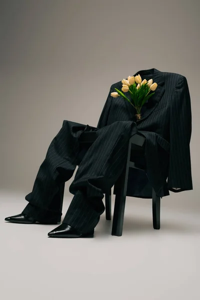 Blooming bouquet of tulips and blue stylish suit hanging on chair on grey — Photo de stock