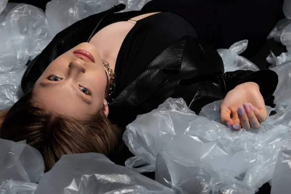 Брюнетка підліток модель в стильному чорному костюмі позує навколо пластикових пакетів — стокове фото