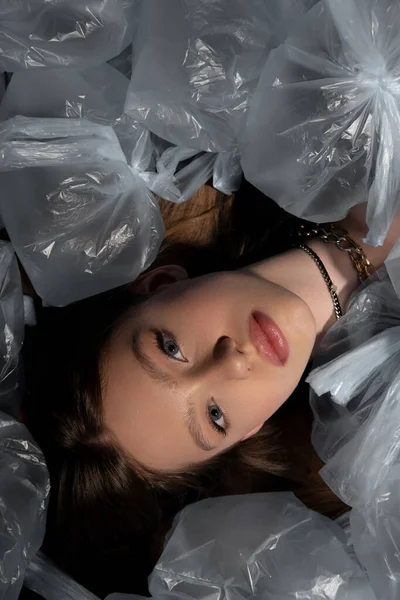 Top view of brunette model lying around plastic bags, recycle fashion concept — Stock Photo