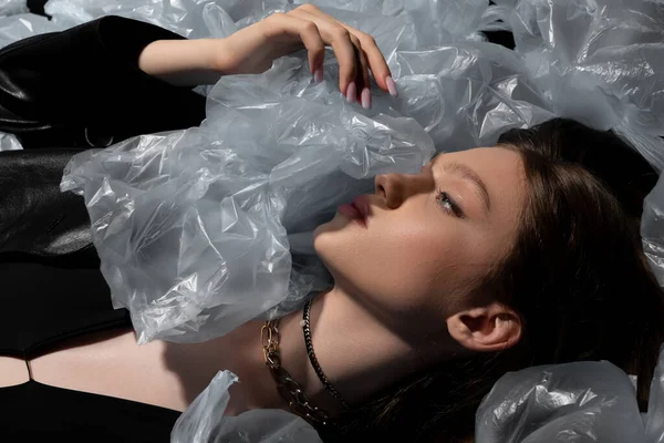 Top view of teenage model lying around plastic bags, recycle fashion concept — Stock Photo