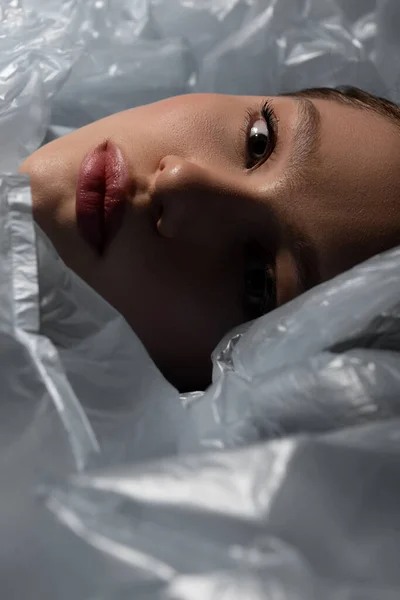 Close up of model lying around plastic bags, recycle fashion concept - foto de stock