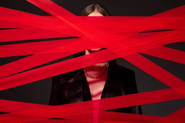 Red strips from duct tape near model isolated on black, recycle fashion concept — Foto stock