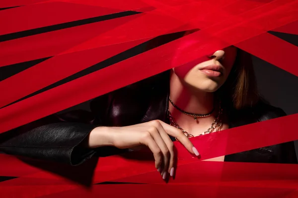 Young model touching red strips from duct tape isolated on black, recycle fashion concept — Foto stock