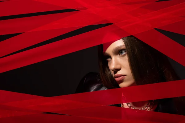 Teenage model looking away through red strips from duct tape isolated on black, recycle fashion concept — Fotografia de Stock