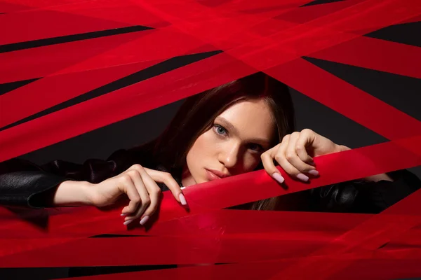 Pretty model touching red strips from duct tape isolated on black, recycle fashion concept — Stock Photo