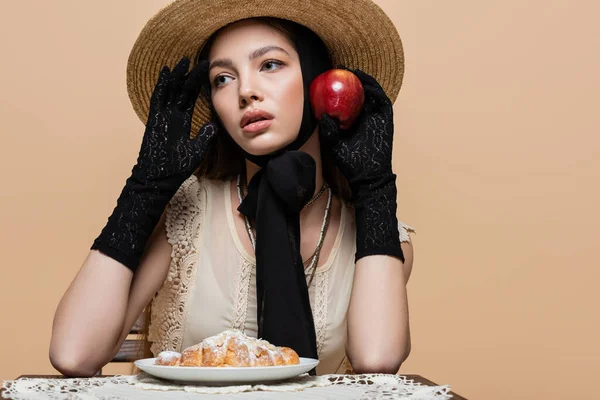 Stylish woman in gloves holding apple near croissant isolated on beige — Photo de stock