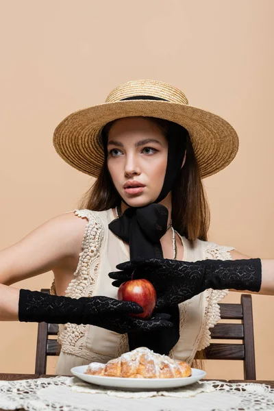 Fashionable woman in gloves holding apple near croissant isolated on beige — Photo de stock