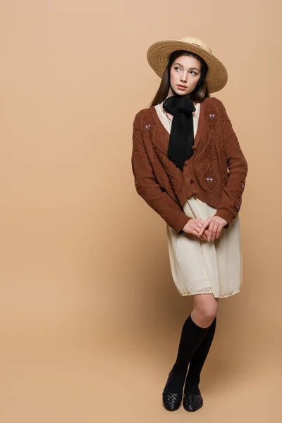 Full length of brunette woman in sun hat posing on beige background - foto de stock