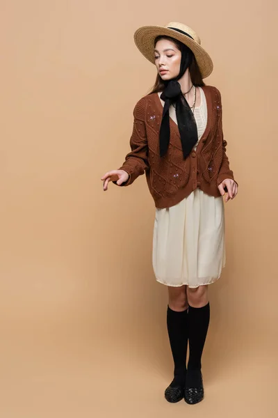 Full length of trendy young woman in sun hat posing on beige background — Stockfoto