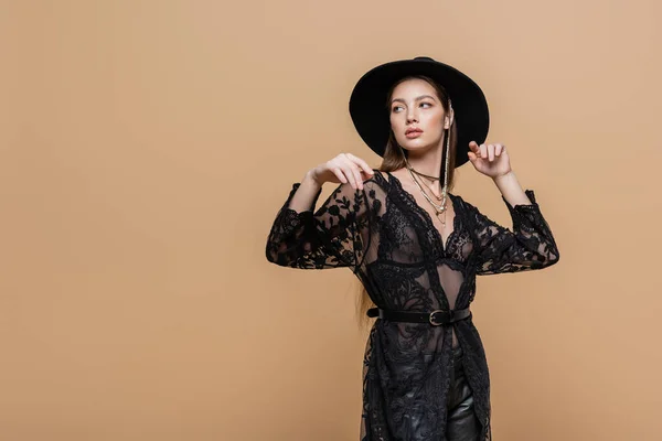 Stylish woman in fedora hat and guipure robe standing isolated on beige — Stock Photo