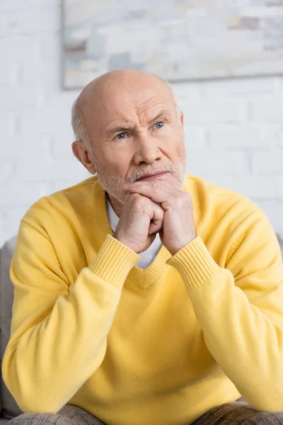 Displeased senior man looking away in living room - foto de stock