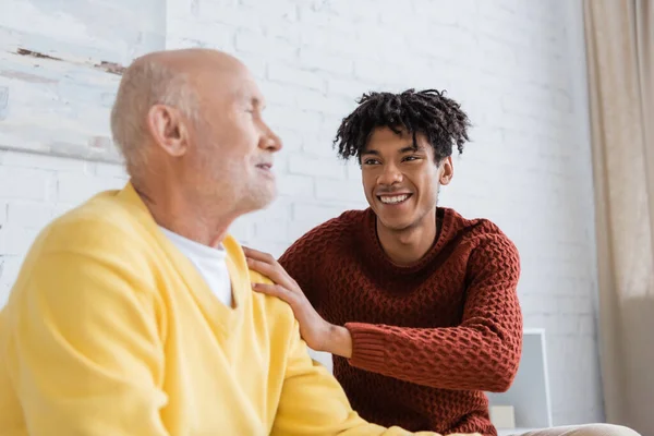 Cheerful african american man hugging blurred granddad at home — Photo de stock