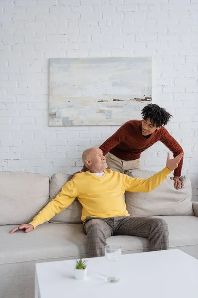 Senior man talking to african american grandson in living room — Stock Photo