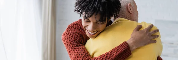 Cheerful african american grandson hugging grandparent at home, banner - foto de stock