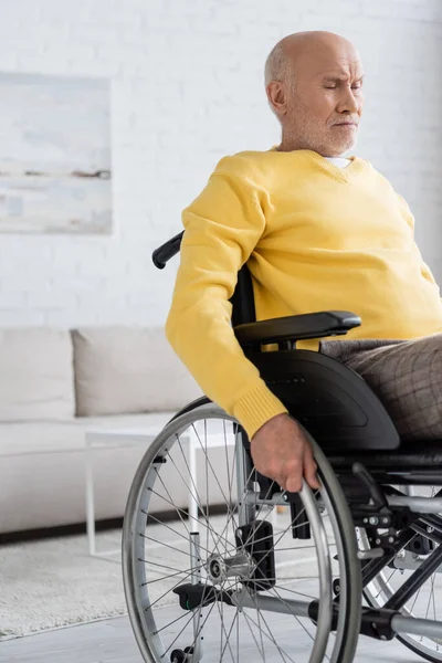 Недовольный пожилой человек сидит дома в инвалидной коляске — стоковое фото
