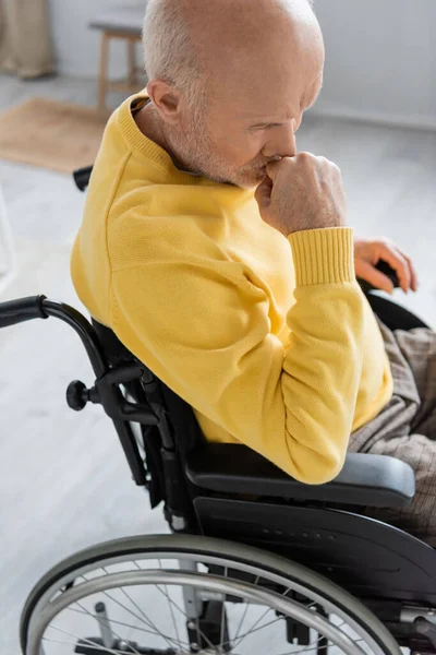 Грустный пенсионер сидит в инвалидной коляске в гостиной — стоковое фото