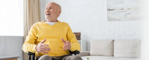 Happy senior man sitting in wheelchair in living room, banner — Stock Photo