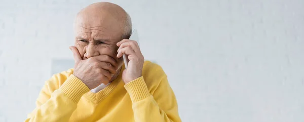 Upset elderly man talking on smartphone in living room, banner — Photo de stock