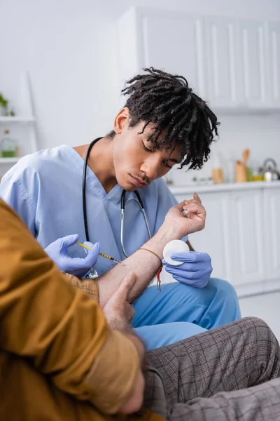 African american nurse doing injection to pensioner at home — Fotografia de Stock