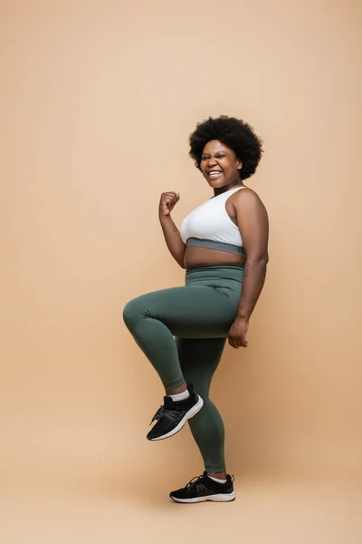 Full length of happy african american plus size woman in sportswear showing yes gesture on beige — Photo de stock