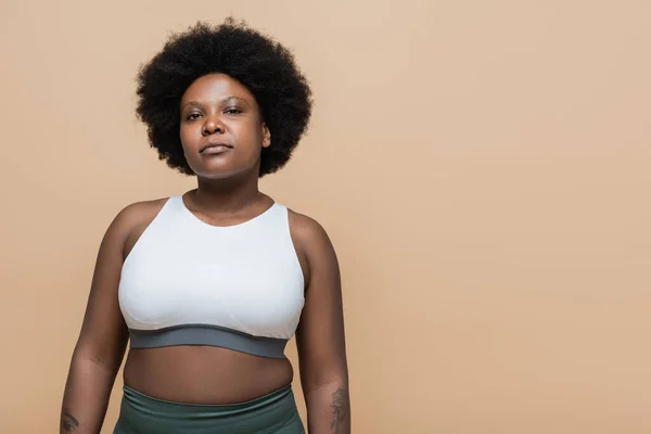 Confident african american plus size woman in crop top isolated on beige — Foto stock