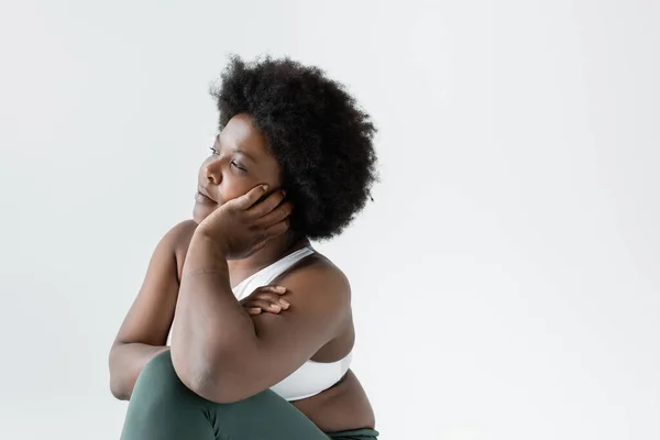 Thoughtful african american plus size woman in sportswear looking away isolated on grey — Stock Photo