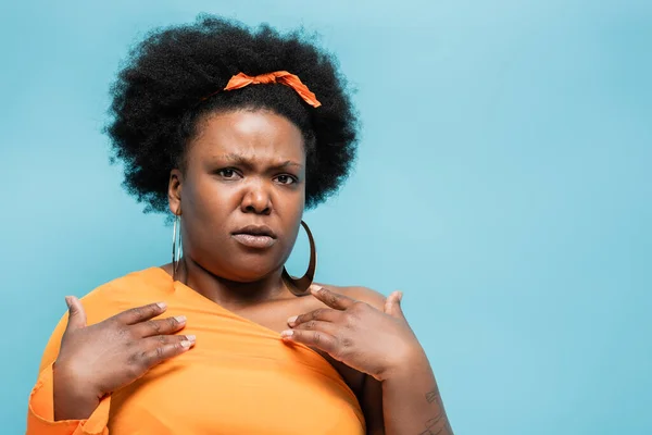 Offended african american body positive woman in hoop earrings pointing at herself isolated on blue — Foto stock