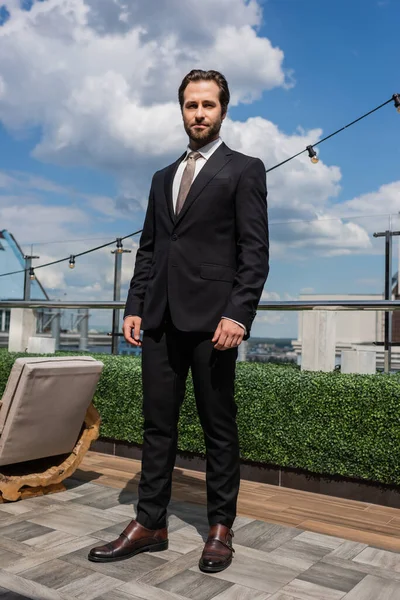 Stylish groom in suit looking at camera on terrace — Foto stock