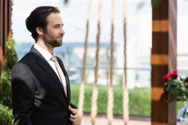 Side view of groom in elegant suit standing on terrace — Stockfoto