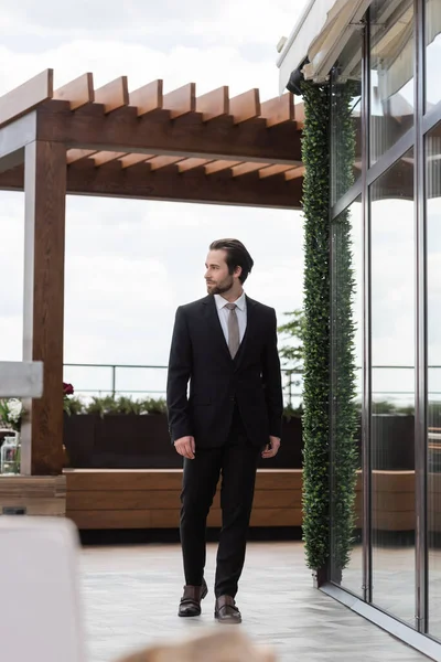 Elegant groom in suit walking on terrace of restaurant — Fotografia de Stock
