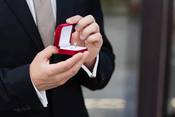 Обрезанный вид человека в костюме держащего коробку с обручальным кольцом на открытом воздухе — стоковое фото