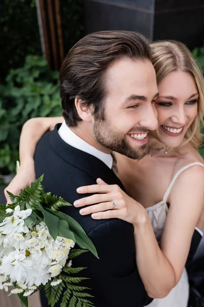 Vista ad alto angolo degli sposi con fiori che si abbracciano all'aperto — Foto stock