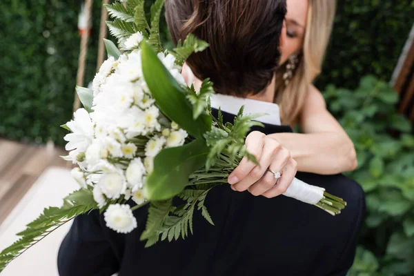 Blurred bride holding bouquet and kissing room outdoors — Stock Photo