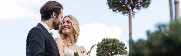 Smiling groom in suit looking at bride on terrace, banner — Stockfoto