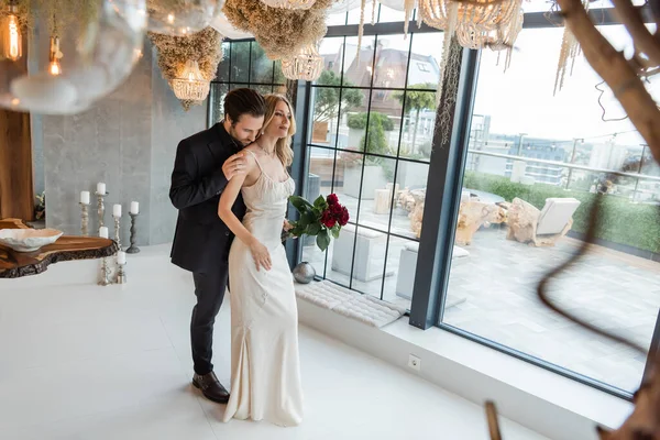 Man in suit touching elegant girlfriend in dress with roses in restaurant — Photo de stock