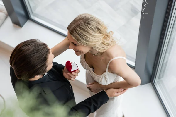 Overhead view of man holding engagement ring near blonde girlfriend in restaurant — Foto stock