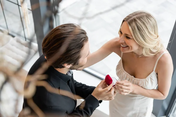 Overhead view of man holding box with proposal ring near smiling girlfriend in restaurant — Fotografia de Stock