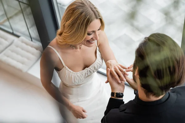 Overhead view of man wearing ring on finger of girlfriend in restaurant — Fotografia de Stock