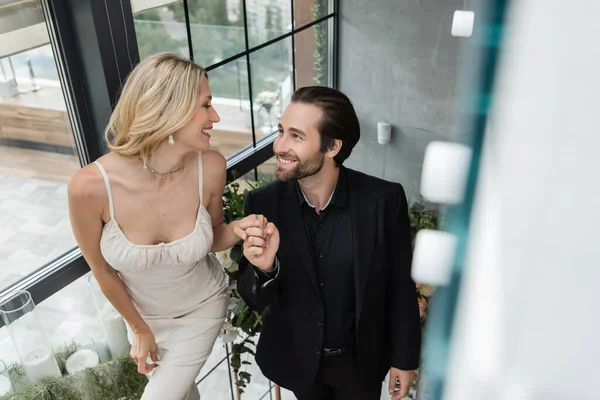 Smiling elegant couple holding hands in restaurant — Stockfoto