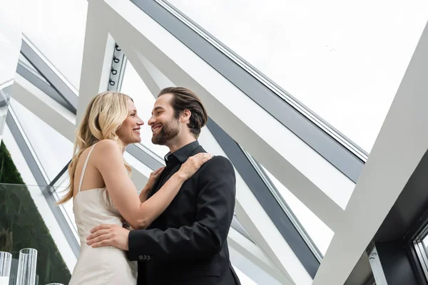 Low angle view of smiling elegant couple hugging in restaurant — Photo de stock