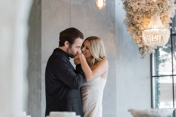 Elegante uomo baciare la mano della fidanzata allegra nel ristorante — Foto stock