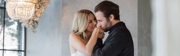 Bearded man in suit kissing hand of smiling girlfriend in restaurant, banner — Stock Photo