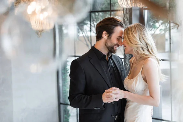 Side view of elegant couple holding hands and smiling in restaurant — Fotografia de Stock