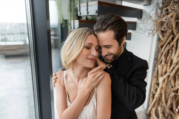 Smiling man in suit hugging blonde girlfriend in restaurant - foto de stock