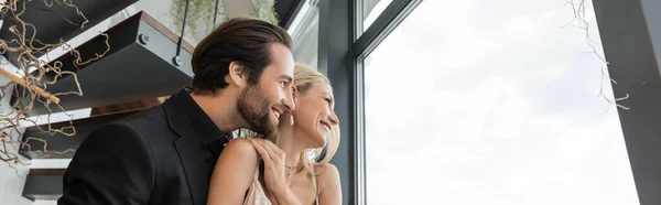 Вид збоку усміхненої романтичної пари, що дивиться на вікно в ресторані, банер — стокове фото