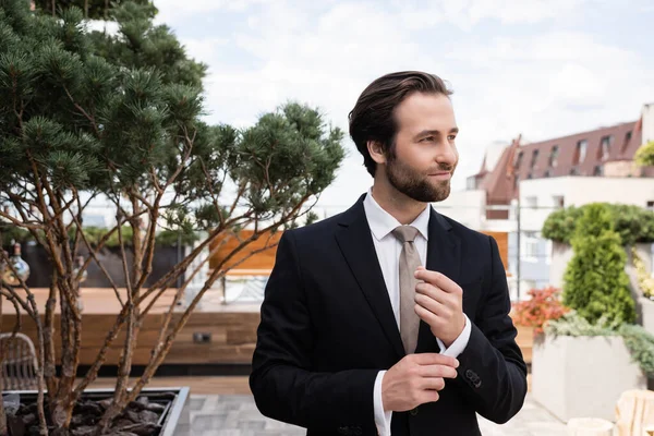 Bearded groom adjusting sleeve of shirt on terrace — Stock Photo