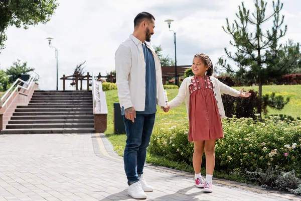 Smiling asian daughter and father holding hands in park — Foto stock