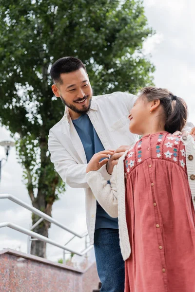 Низький кут зору усміхнений азіатський тато дивиться на дочку в літньому парку — стокове фото
